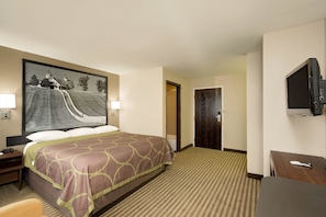 Une chambre d’hôtel avec un grand lit, un bureau, une télévision et un tableau représentant un paysage accroché au mur.