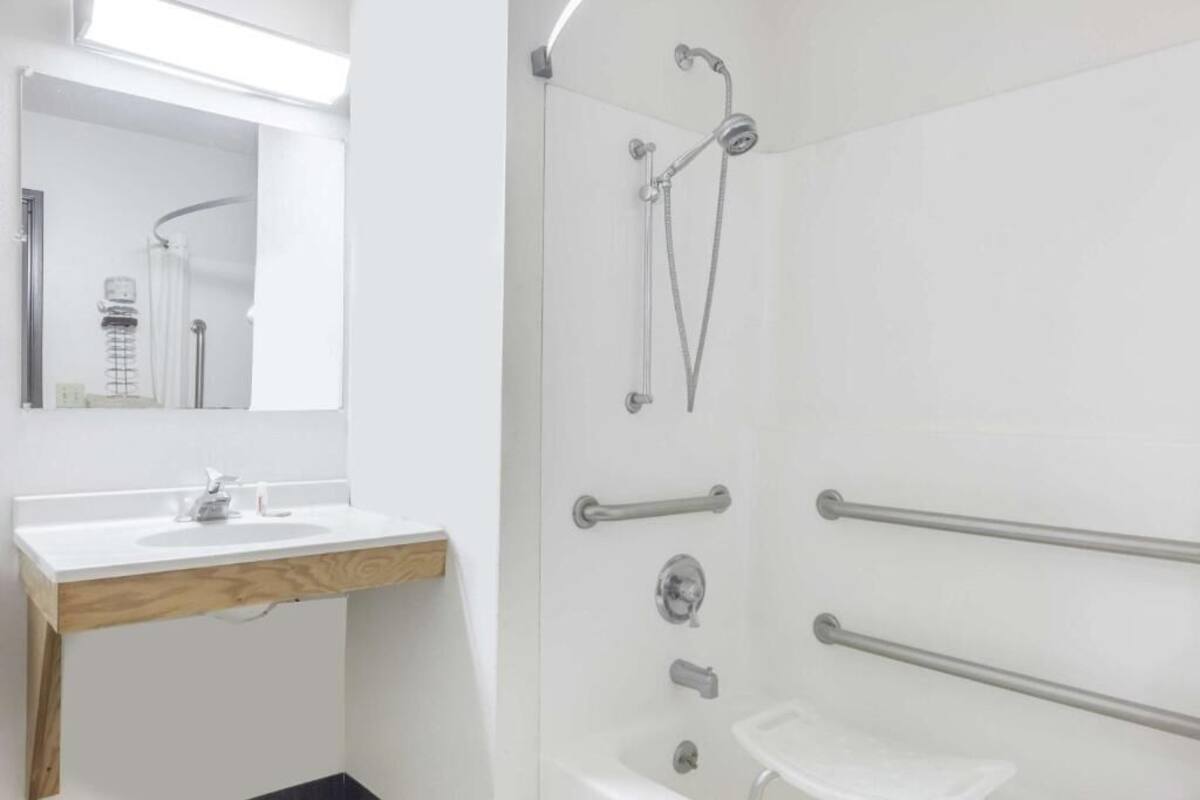 A modern bathroom with a white sink, mirror, and shower.