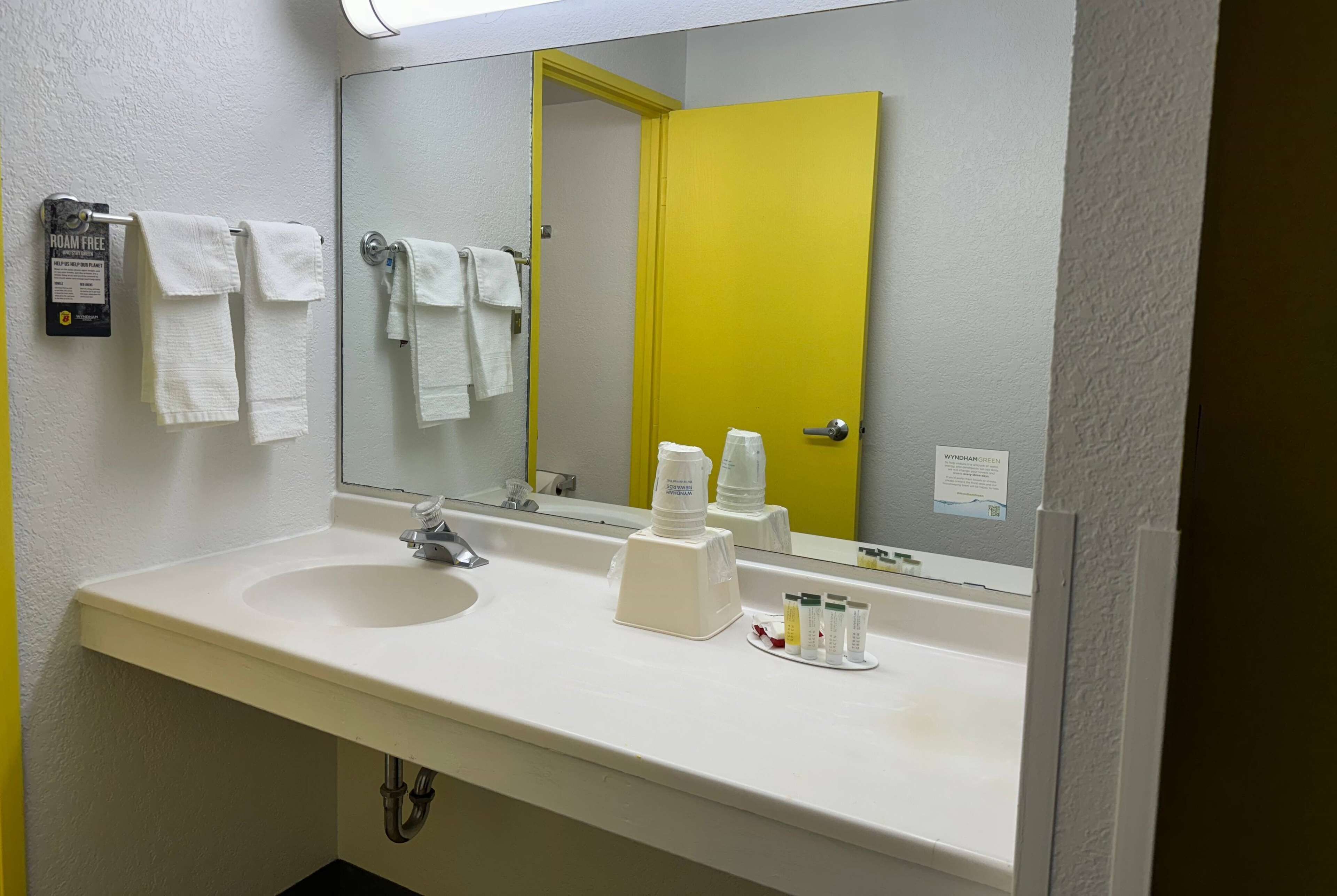 Un baño con un lavamanos blanco, un espejo y una puerta amarilla.