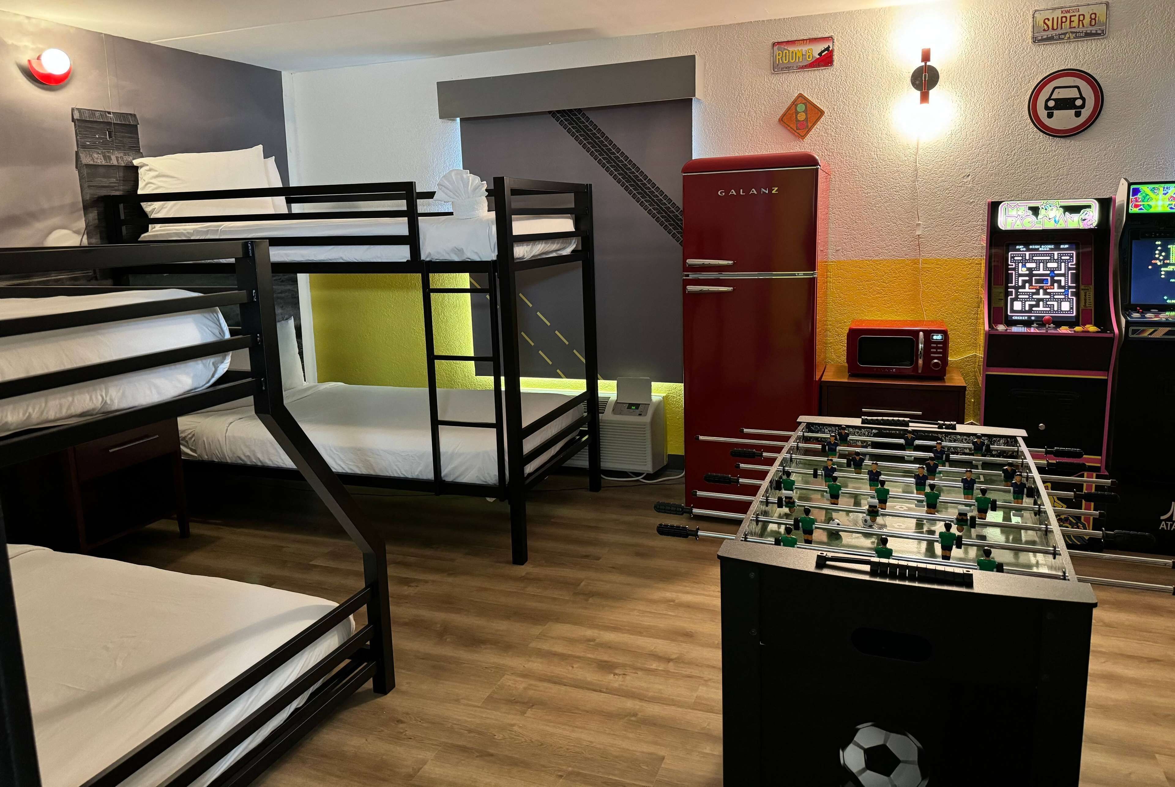 A room with bunk beds, a foosball table, a microwave, and a refrigerator.