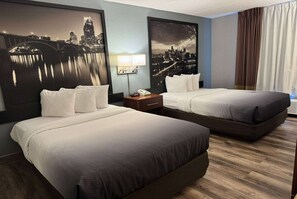 A hotel room with two beds, a nightstand, a lamp, and two large cityscape paintings on the walls. - Super 8 by Wyndham Bloomington/Airport (Bloomington)