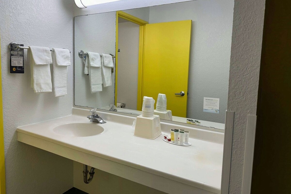 A bathroom with a white sink, a mirror, and a yellow door.