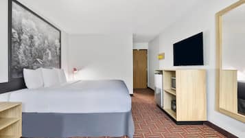 Una habitació d'hotel amb un llit, una televisió, una taula i un quadre gran a la paret.