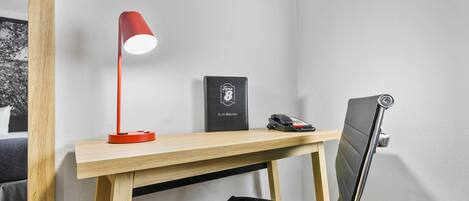 A wooden desk with a red desk lamp, a black phone, and a black book titled "G. A. Z. Directory" on it.