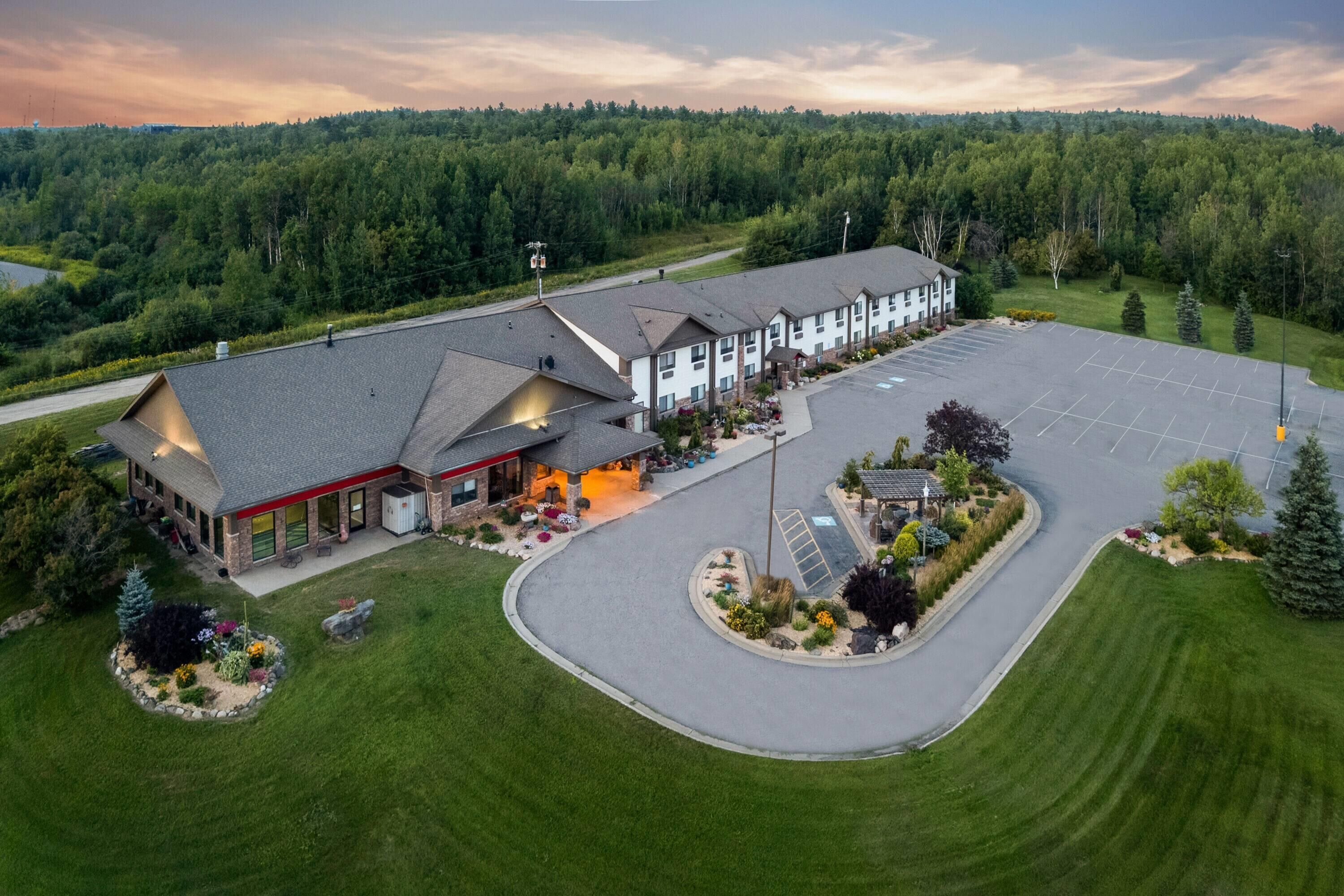 A large hotel with multiple buildings, a parking lot, and a landscaped area with trees and shrubs.