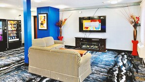 A hotel lobby with striped sofas, a flat-screen TV, a fireplace, and a vending machine. - Coratel Inn & Suites By Jasper Northfield (Northfield)
