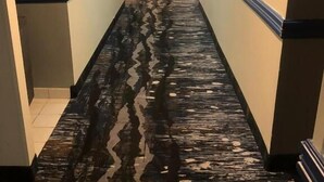 Ein Hotelkorridor mit nassen Boden, Wänden mit blauen Akzenten und Türen an beiden Seiten.