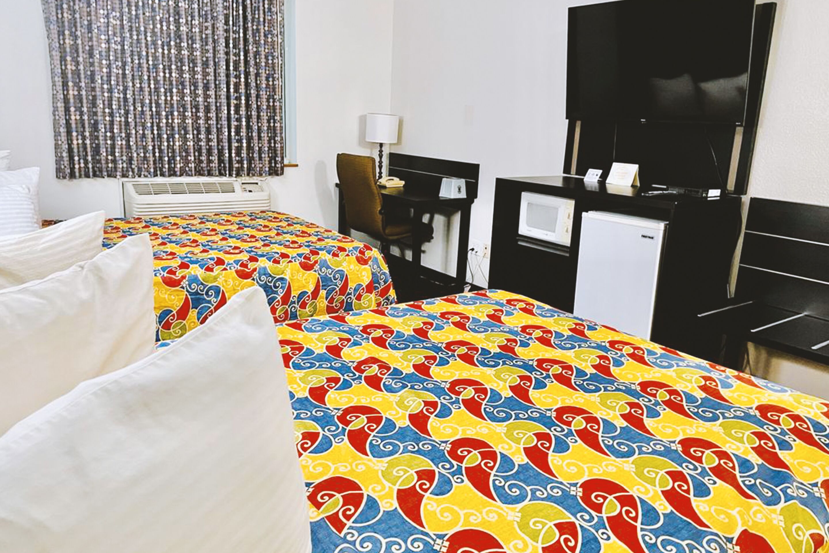 Une chambre d’hôtel avec deux lits, un bureau, une télévision et un minibar.