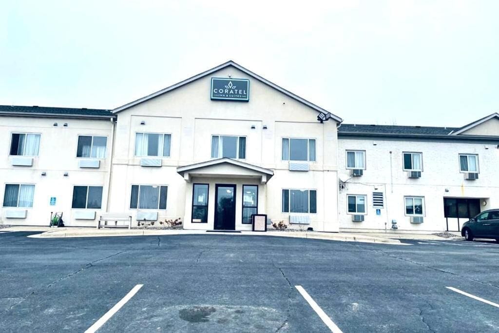 Hotel amb entrada central, nombroses finestres i un aparcament.