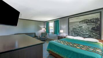 A hotel room with a bed, desk, chair, and a large window with curtains.