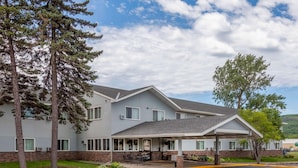 A two-story building with a covered patio area, a parking lot, and a grassy area with trees. - Super 8 by Wyndham Duluth (Duluth)