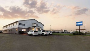 A Travelodge hotel with a parking lot and several vehicles. - Travelodge by Wyndham Redwood Falls (Redwood Falls)