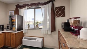 A kitchen with a refrigerator, microwave, coffee maker, and a large window with curtains. - Travelodge by Wyndham Redwood Falls (Redwood Falls)