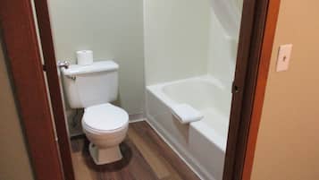 Een badkamer met een toilet, een bad en een douchegordijn.