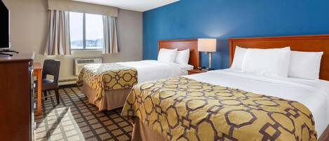 A hotel room with two beds, a desk, a chair, and a window with curtains.