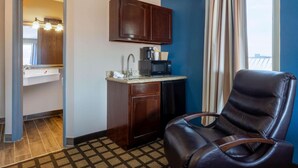 A compact hotel room with a kitchenette, a leather chair, and a view of the balcony. - Baymont by Wyndham Rochester Mayo Clinic Area (Rochester)