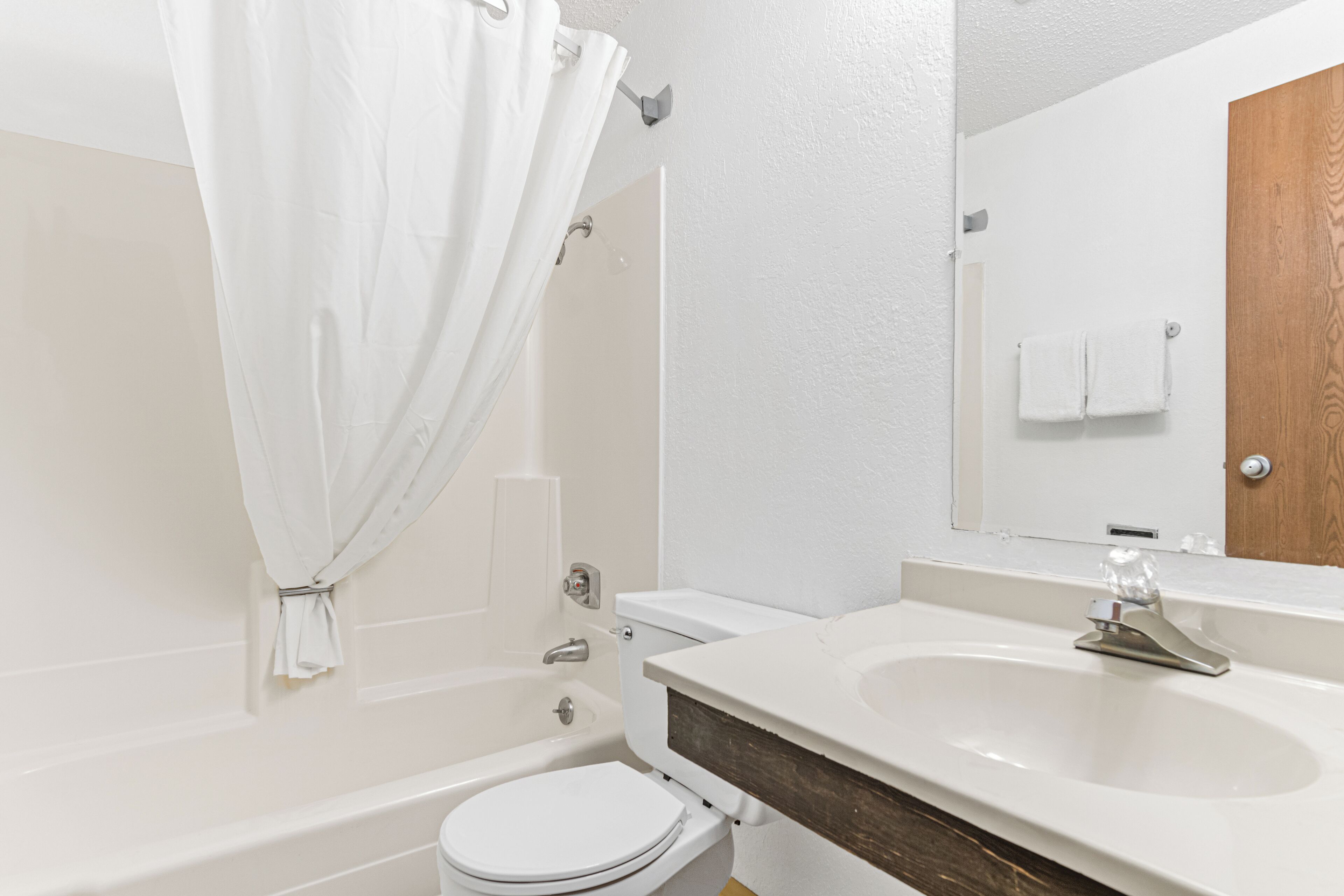 Une salle de bain avec une baignoire, des toilettes, un lavabo et une porte en bois.