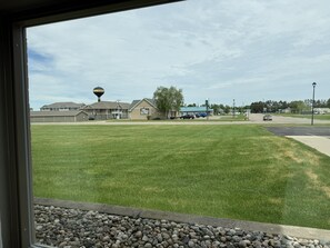 A grassy area with a building in the background, a water tower, and a few cars parked. - Super 8 by Wyndham Perham (Perham)