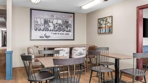 Un comedor con un cartel grande, mesas y sillas de madera.