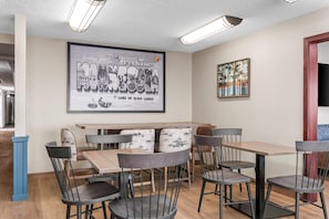 Un comedor con un cartel grande, mesas y sillas de madera.