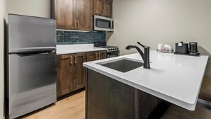 Una cocina moderna con electrodomésticos de acero inoxidable, armarios de madera y encimera blanca.