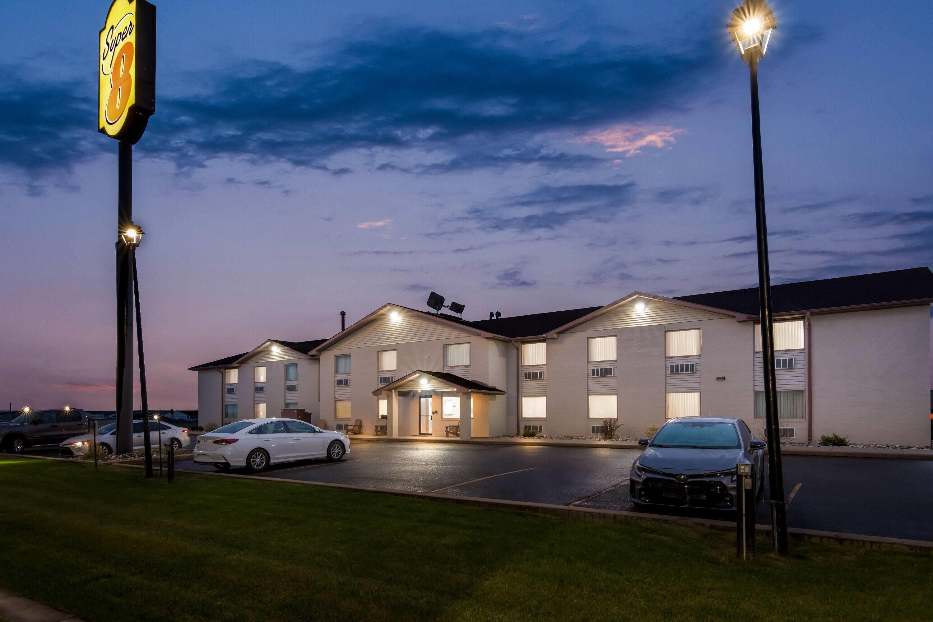 A hotel with a parking lot, a building entrance, and a sign.