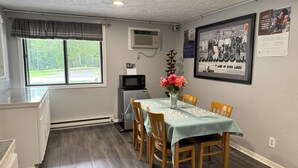 Un coin repas avec une table dressée pour quatre personnes, un four à micro-ondes et un tableau encadré au mur.