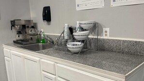 Une cuisine équipée d’une machine à café en acier inoxydable, d’un égouttoir et d’un évier.