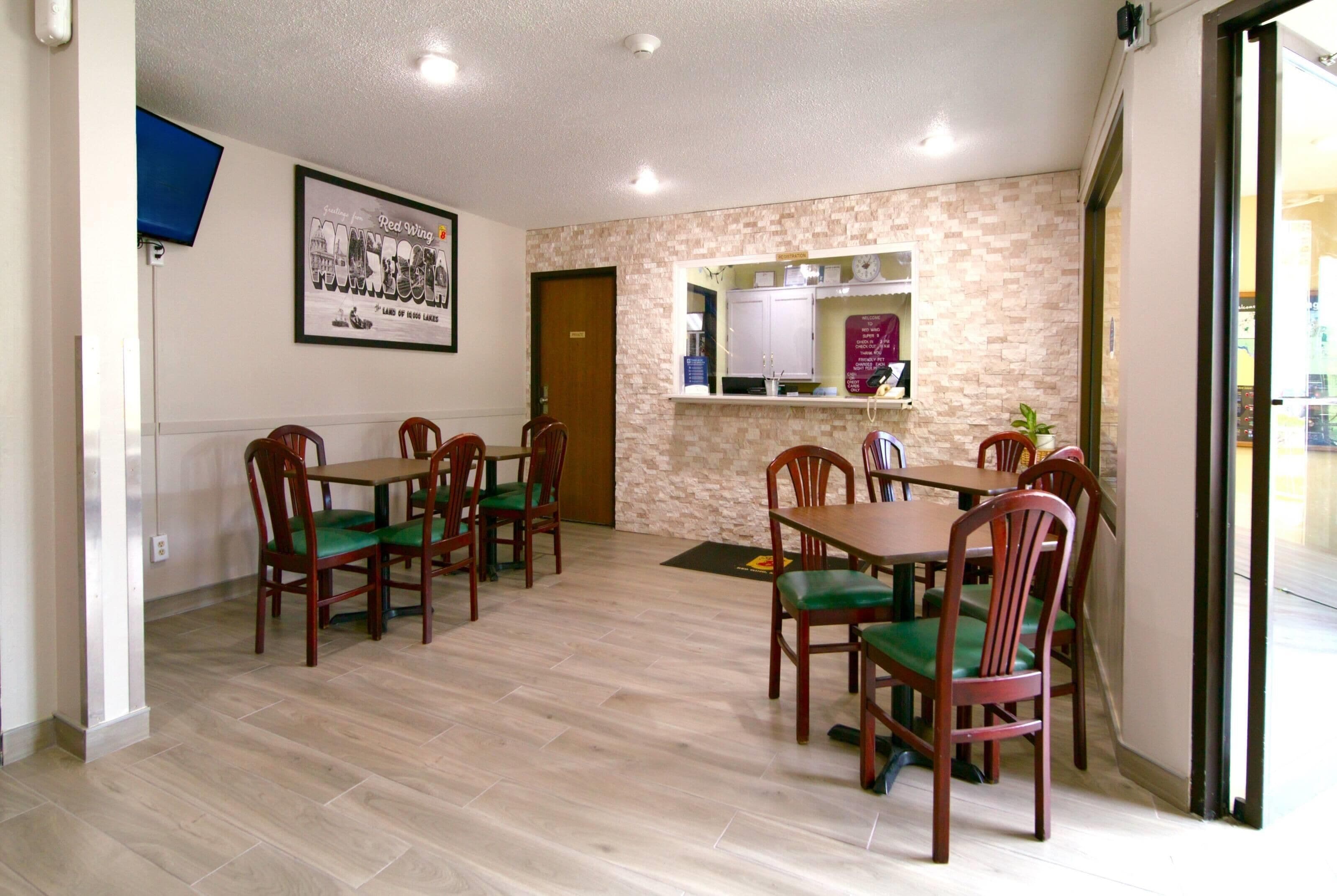 A dining area with wooden tables and chairs, a stone accent wall, and a mounted picture.