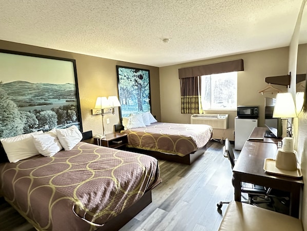 A hotel room with two beds, a desk, a chair, a microwave, and a large window.