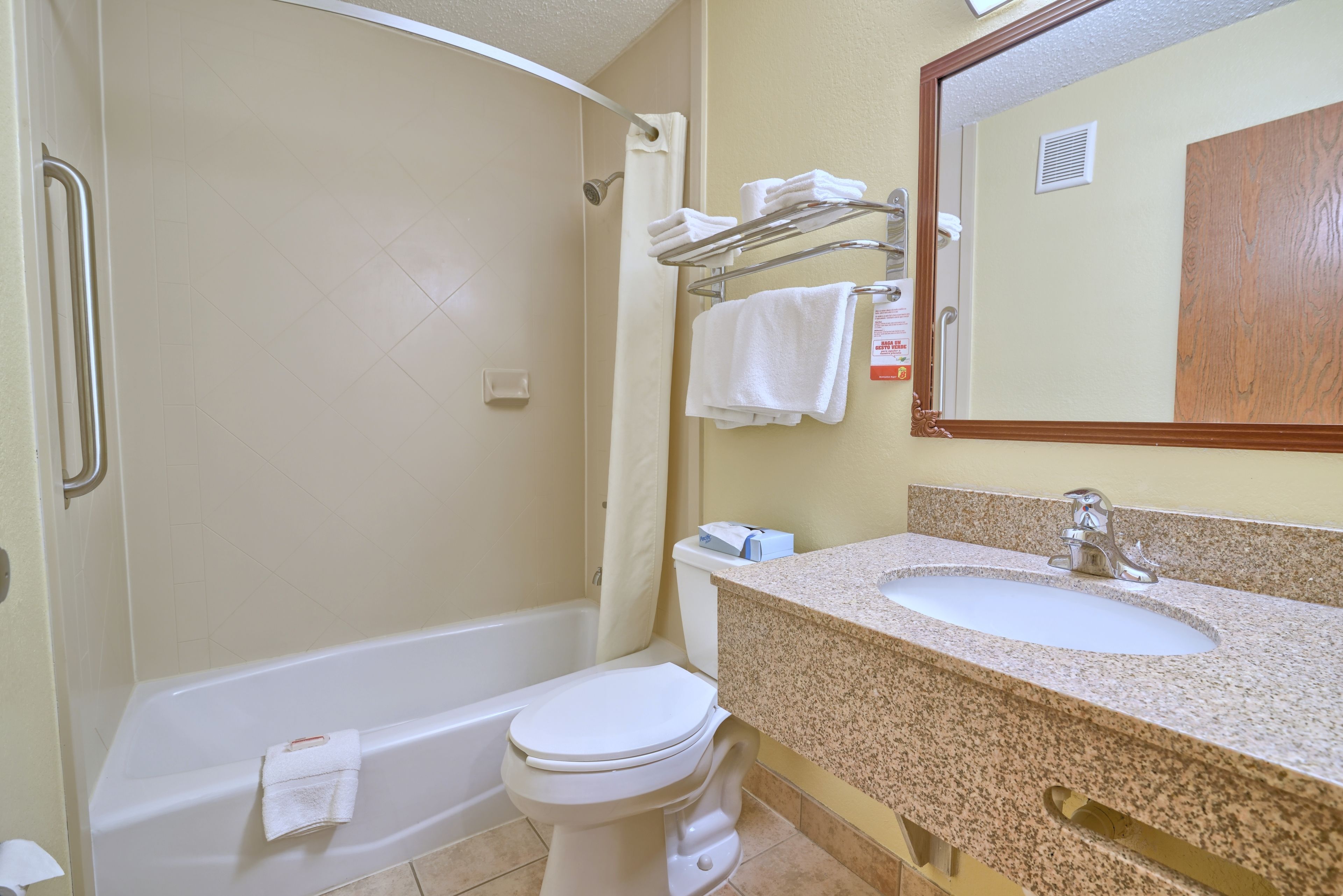 A bathroom with a bathtub, toilet, sink, and a mirror.