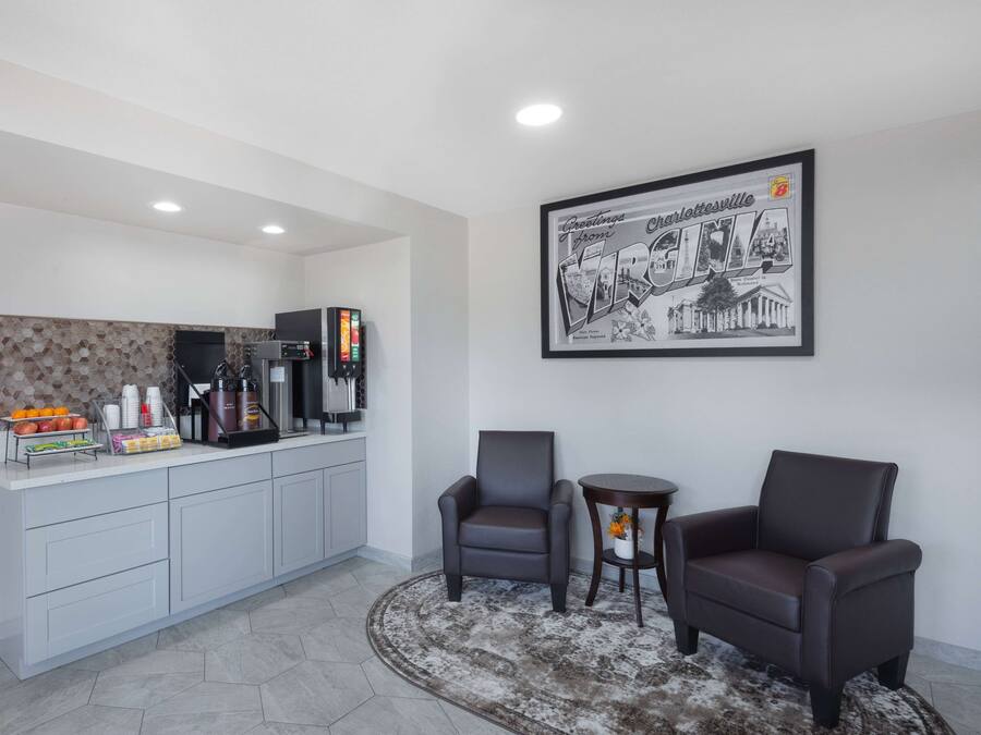 Una cucina moderna con angolo caffè, due poltrone in pelle, un piccolo tavolino rotondo e un cartello di benvenuto incorniciato.
