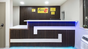 A reception desk with a wooden panel design, a blue illuminated section, and two signs above it. - Super 8 by Wyndham Charlottesville (Charlottesville)