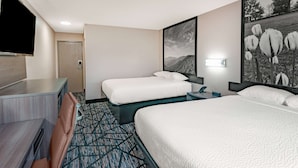 A hotel room with two single beds, a TV, a desk, and a patterned carpet. - Super 8 by Wyndham Charlottesville (Charlottesville)