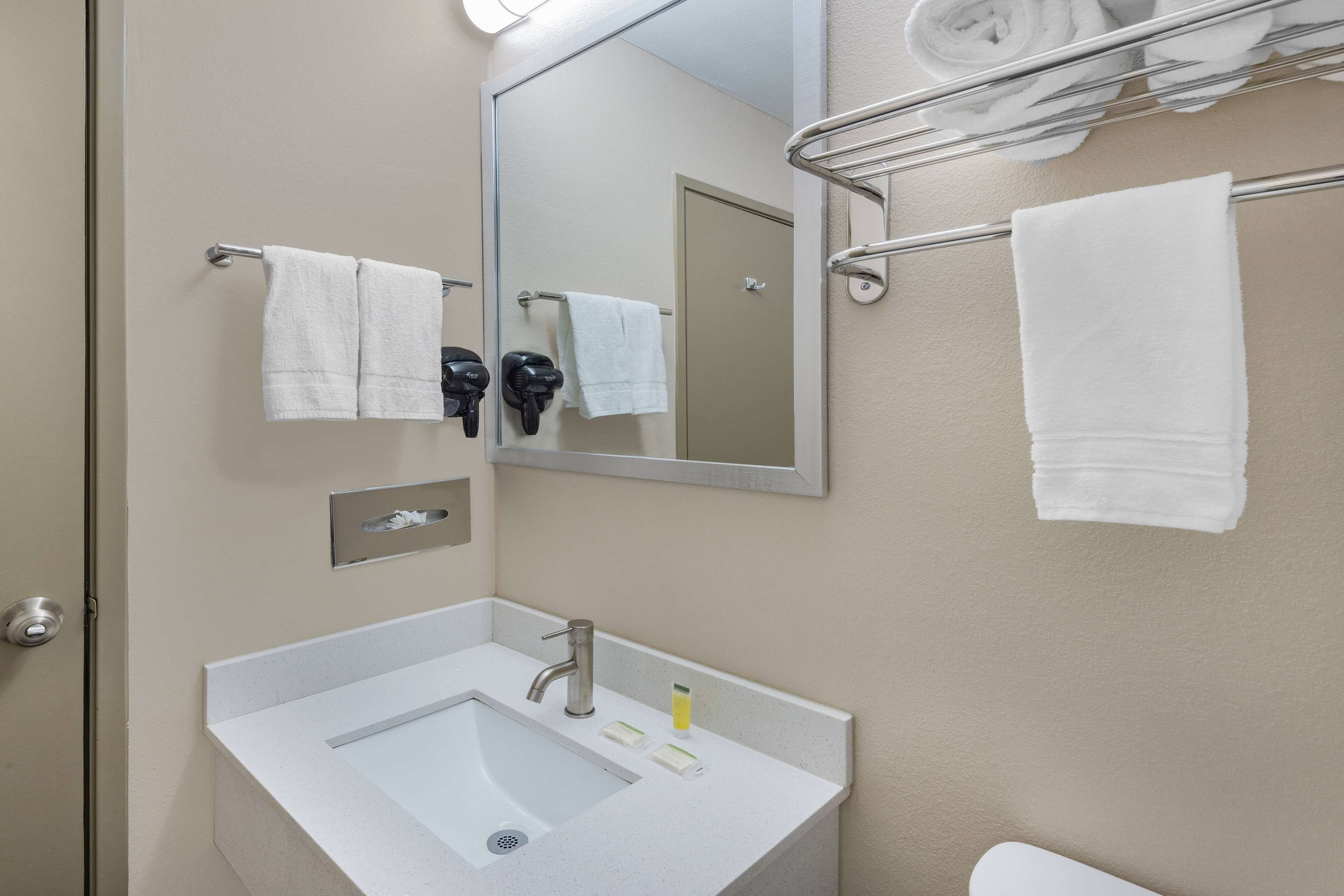 A bathroom with a sink, mirror, towel rack, and a door.