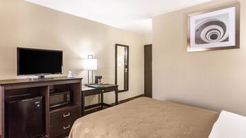 Une chambre d’hôtel équipée d’un lit, d’une télévision, d’un bureau avec une lampe, d’un four à micro-ondes et d’un réfrigérateur.