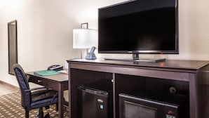 Une chambre d’hôtel équipée d’un bureau, d’une télévision à écran plat, d’un mini-réfrigérateur, d’un four à micro-ondes, d’une chaise et d’une lampe.