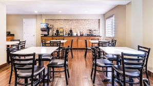 Un espace repas comprenant plusieurs tables et chaises, un comptoir de cuisine avec des appareils électroménagers et un pare-feu en pierre.