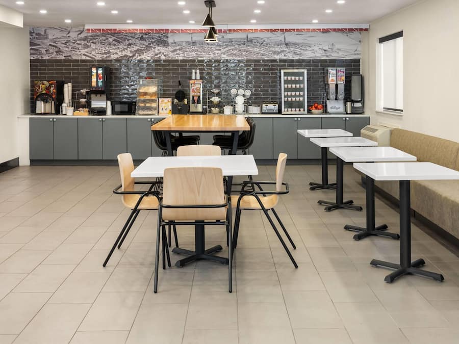 A modern restaurant with a long counter, multiple tables, and a seating area with a sofa.