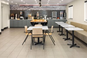 Un restaurante moderno con una barra larga, varias mesas y una zona de estar con sofá.