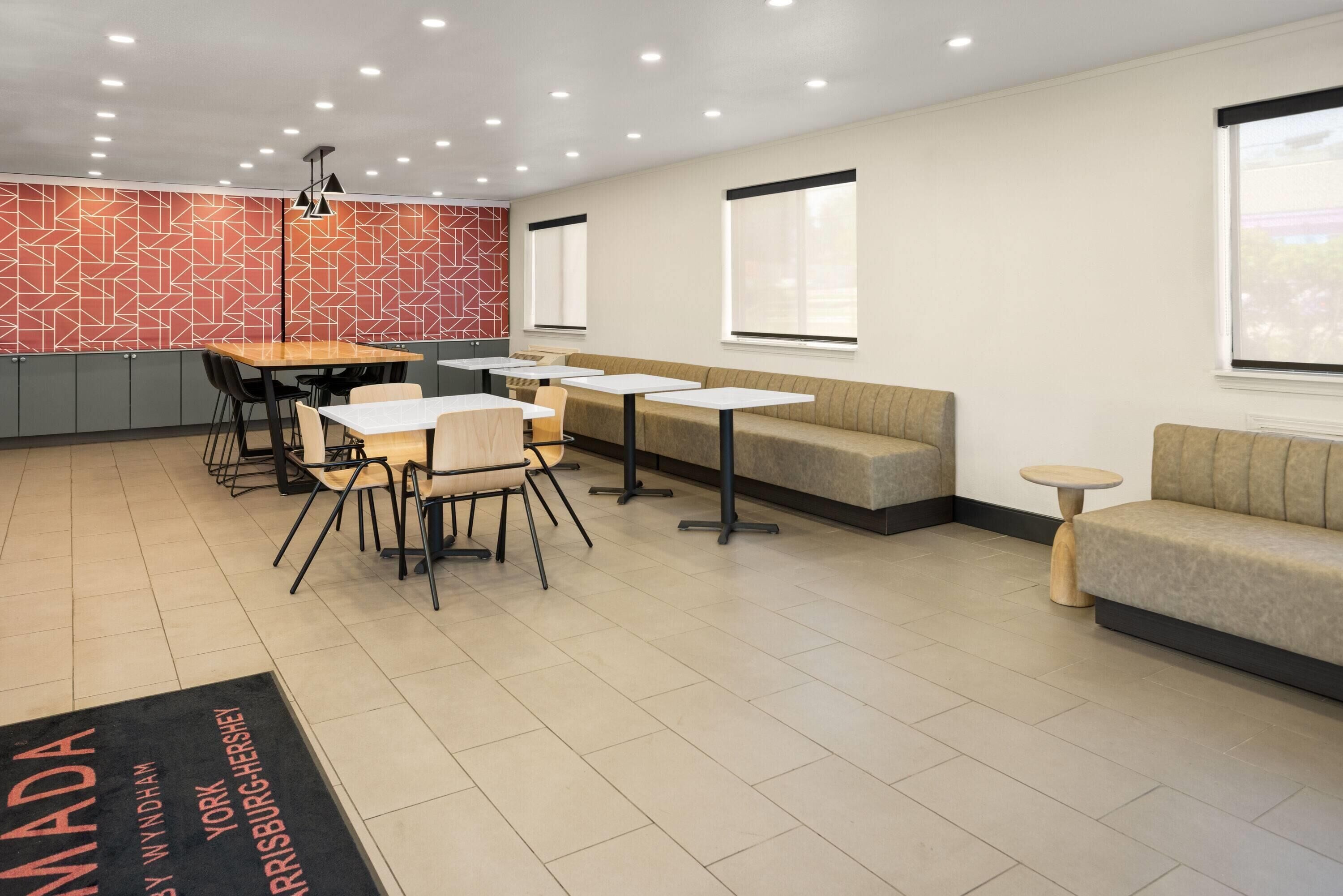 Ein modernes Interieur mit einem Essbereich mit Tischen und Stühlen, einer Sitzecke mit Sofas und einer Wand mit Musterdesign.