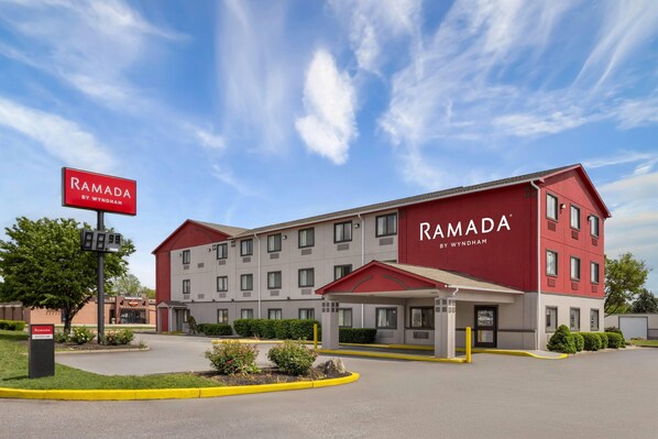 A Ramada hotel with a red and white facade, multiple floors, and a covered entrance.