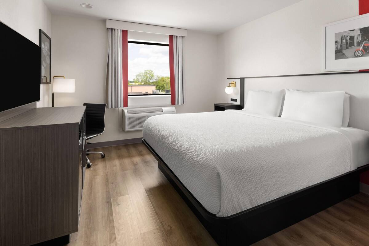 A modern hotel room with a large bed, a desk, and a chair.