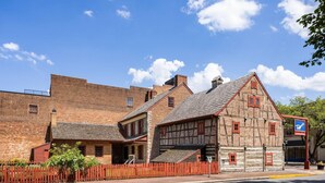 En historisk bygning med en murstensfacade, et træhus med et stejlt tag og et rødt plankeværk.