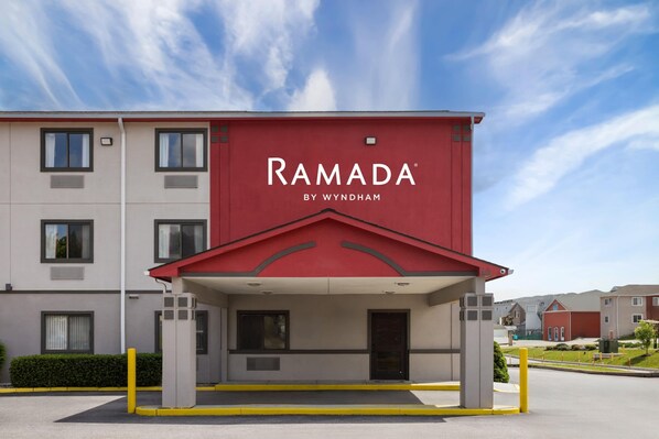A Ramada by Wyndham hotel with a red facade and a covered entrance. - Ramada by Wyndham York Harrisburg Hershey (York)