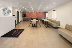 A modern reception area with a world map, a reception desk, a seating area with tables and chairs, and a counter with a menu board.