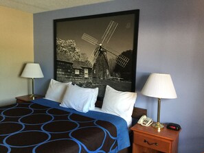A hotel room with a bed, two bedside tables with lamps, a wall-mounted telephone, and a large black and white windmill painting. - Super 8 by Wyndham Middletown (Middletown)
