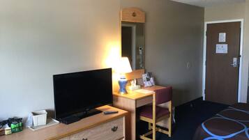 Una habitación de hotel con televisión, escritorio con lámpara, silla y cama.