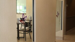 A hallway with beige walls and a tiled floor. There is a door with a glass panel and a sign that reads "Welcome." - Super 8 by Wyndham Plattsburgh (Plattsburgh)