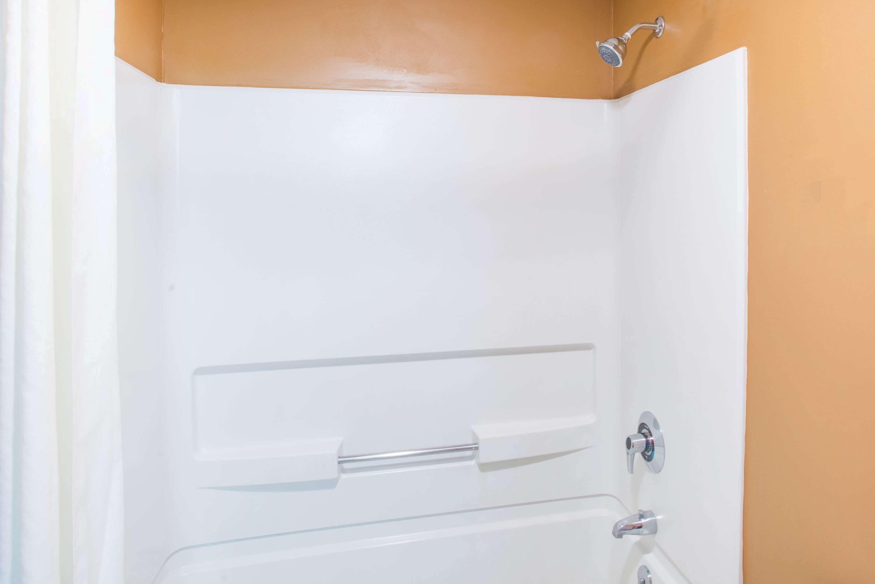 Una bañera blanca con cabezal de ducha, toallero y grifo.